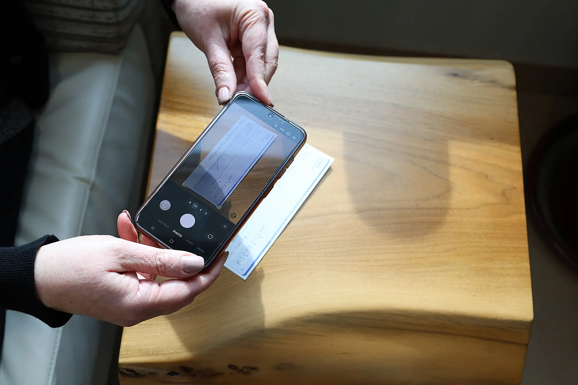 Member holding their smartphone over a cheque to deposit it remotely into their account